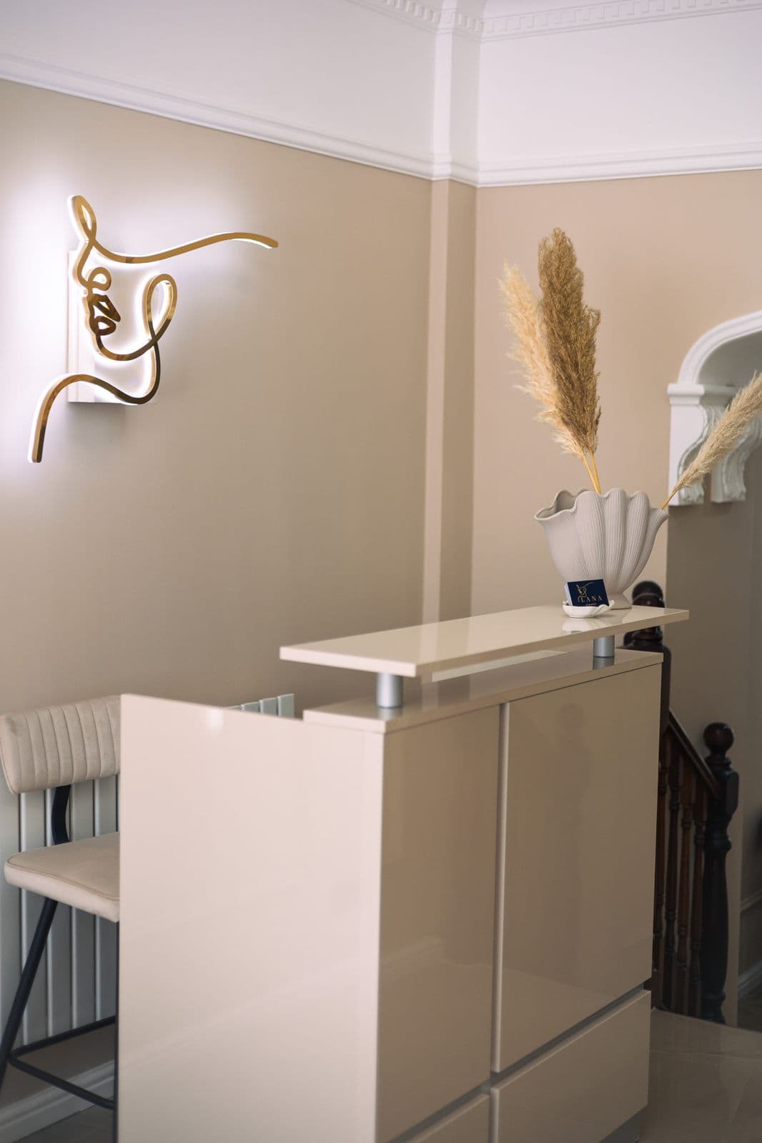 The clinic reception, with the gold line-art wall light above the desk