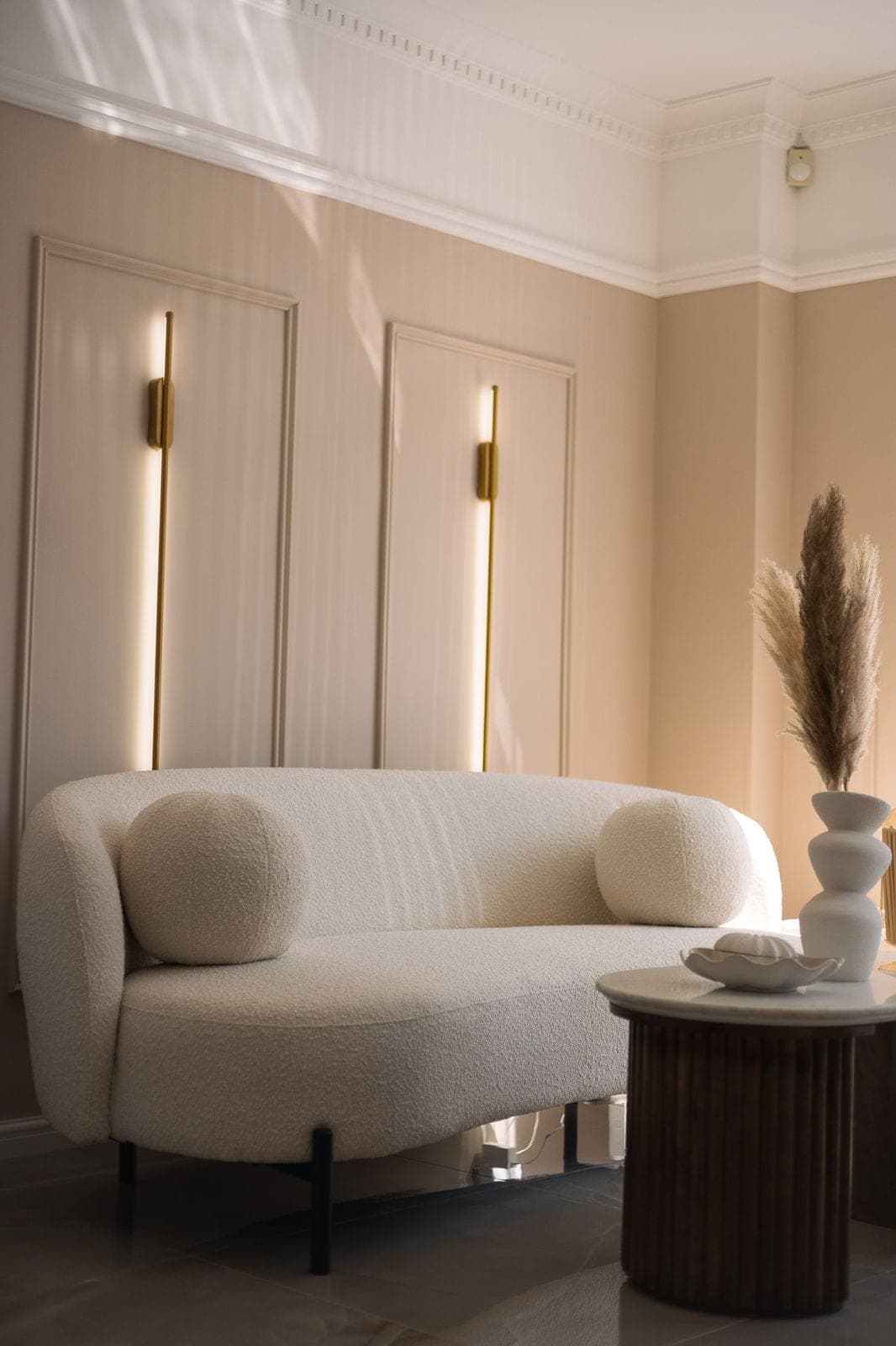 The clinic's cream boucle lounge seating, styled with pampas grass and gold wall lighting.
